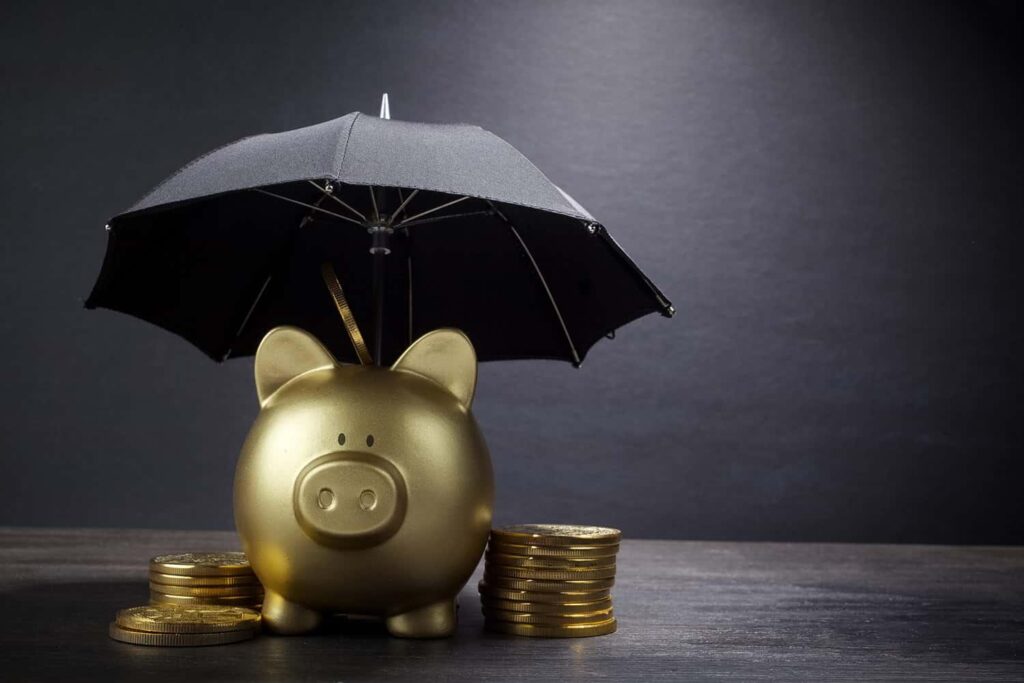 Golden piggy bank under a black umbrella surrounded by stacks of gold coins, symbolising financial protection and savings security.